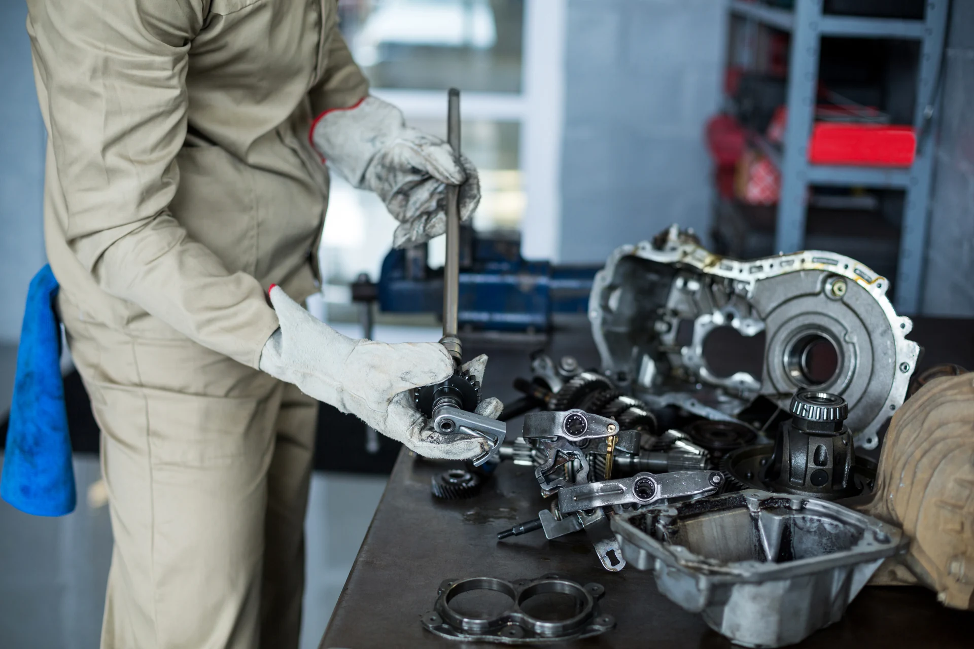 Mechanic assembling transmission components on a workshop table.